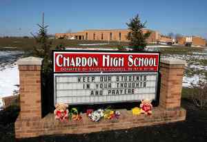 Flowers and gifts sit along the Chardon High School sign along with a message of thought and prayer in Chardon